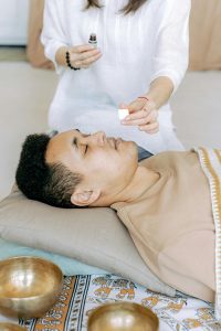 An adult man experiencing a calming aromatherapy session with essential oils indoors.