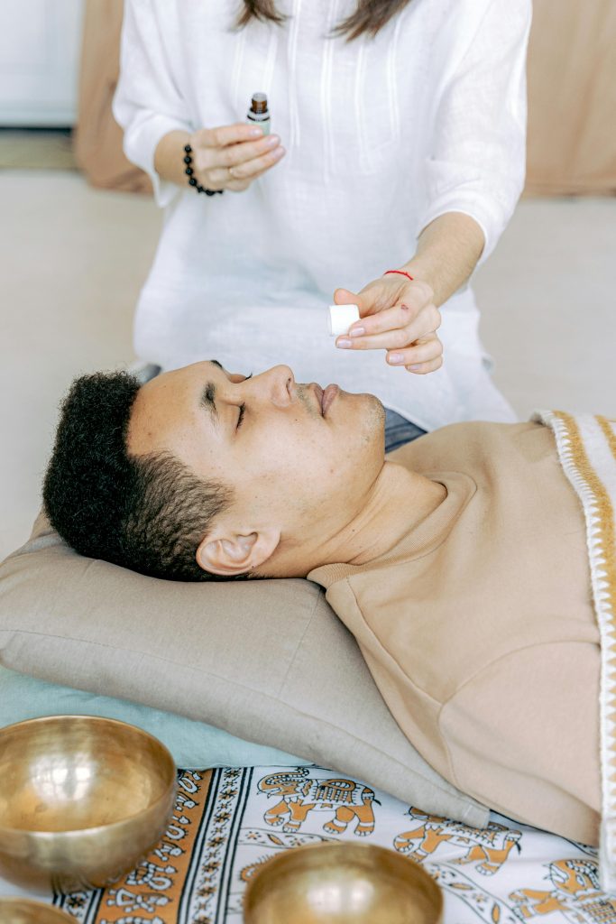 An adult man experiencing a calming aromatherapy session with essential oils indoors.
